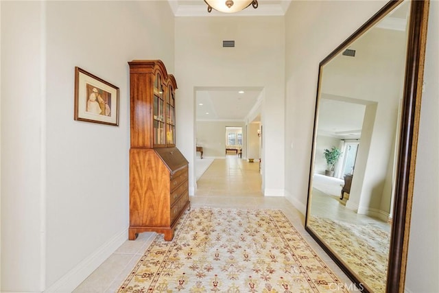 corridor featuring light tile patterned floors and crown molding