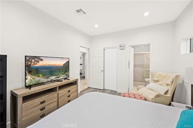 bedroom with ensuite bathroom and light hardwood / wood-style floors