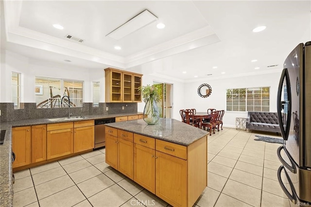 kitchen with black fridge, stainless steel dishwasher, and a raised ceiling