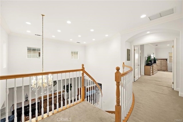 hall with light carpet, crown molding, a chandelier, and electric panel