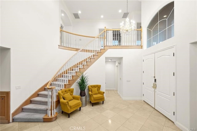 foyer with light tile patterned floors, a towering ceiling, a chandelier, and ornamental molding