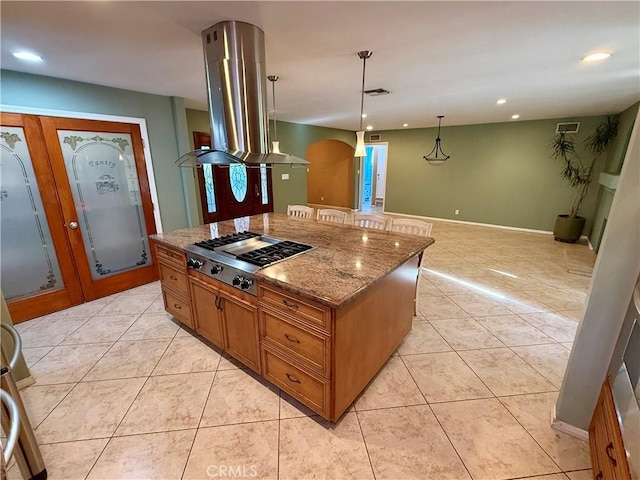 kitchen featuring light stone countertops, a center island, hanging light fixtures, island range hood, and stainless steel gas stovetop