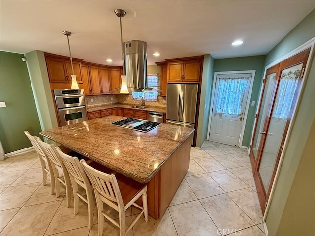 kitchen with stainless steel appliances, sink, a kitchen bar, and a center island