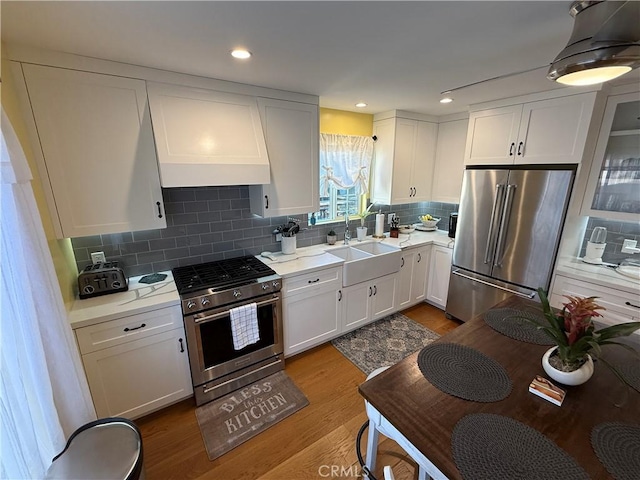 kitchen with premium range hood, stainless steel appliances, backsplash, white cabinets, and sink