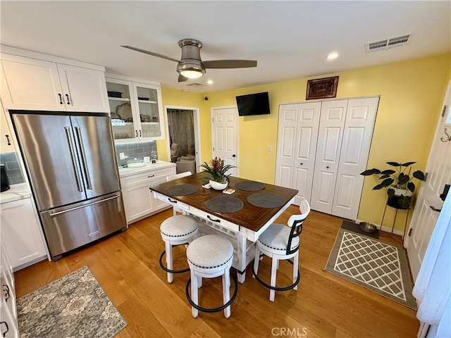 kitchen with high end fridge, ceiling fan, decorative backsplash, light wood-type flooring, and white cabinets