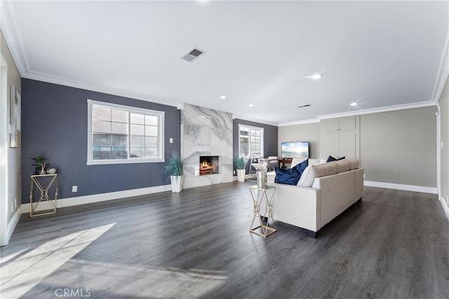 living room featuring dark wood-type flooring, crown molding, and a fireplace