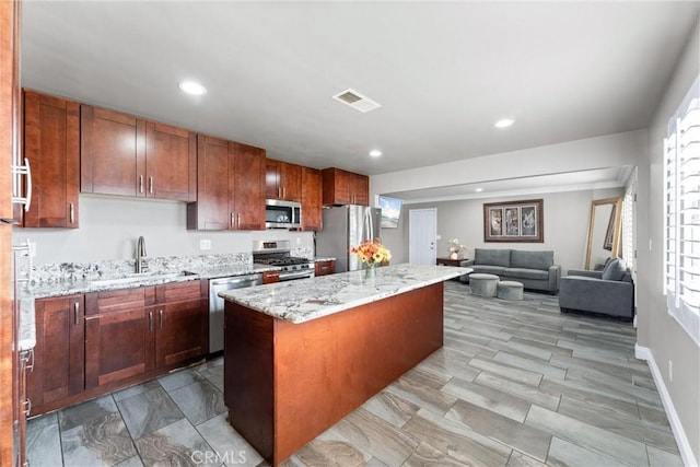 kitchen featuring light stone countertops, sink, stainless steel appliances, and a kitchen island