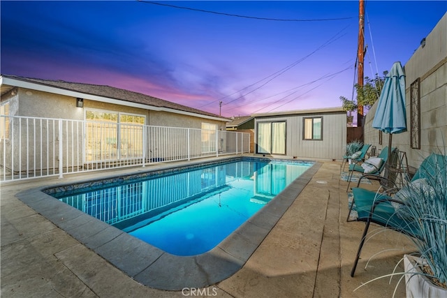 pool at dusk featuring an outbuilding and a patio