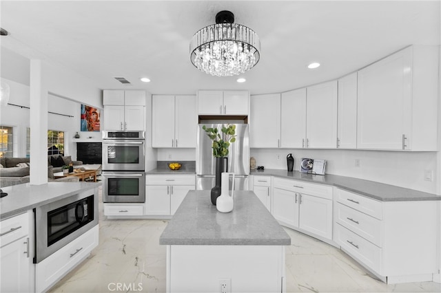 kitchen featuring a notable chandelier, stainless steel appliances, and white cabinetry