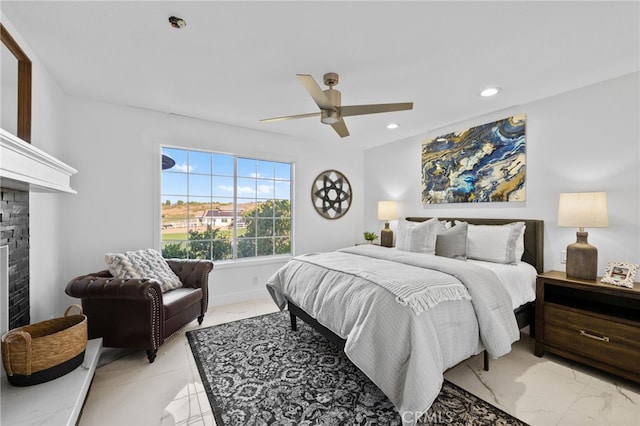 bedroom featuring ceiling fan and a stone fireplace