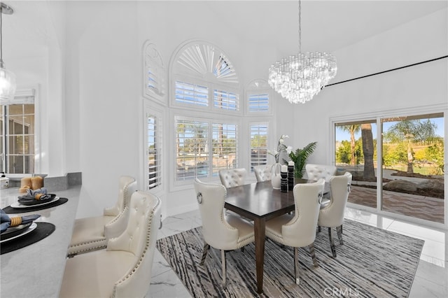 dining area with a chandelier, a towering ceiling, and a healthy amount of sunlight