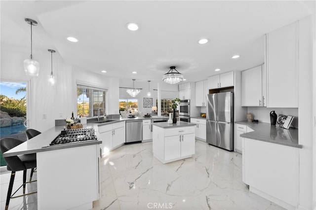 kitchen featuring kitchen peninsula, appliances with stainless steel finishes, hanging light fixtures, white cabinets, and a breakfast bar