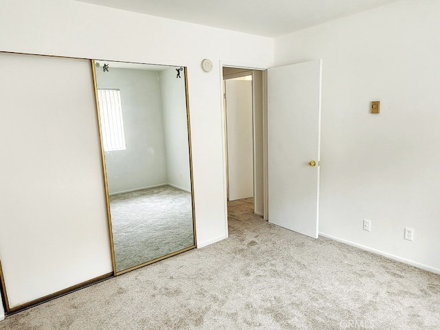 unfurnished bedroom featuring light carpet and a closet