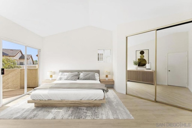 bedroom featuring access to outside, a closet, light hardwood / wood-style flooring, and lofted ceiling