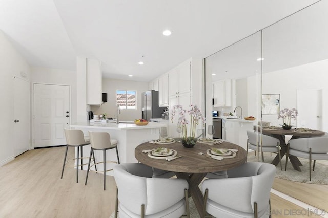 kitchen featuring white cabinets, stainless steel appliances, light hardwood / wood-style floors, sink, and kitchen peninsula