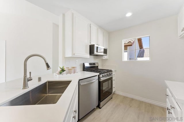 kitchen featuring sink, white cabinets, appliances with stainless steel finishes, and light hardwood / wood-style flooring