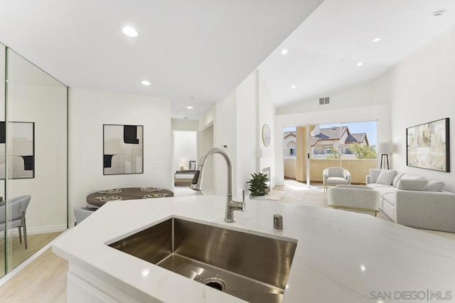 kitchen with lofted ceiling, light hardwood / wood-style floors, and sink