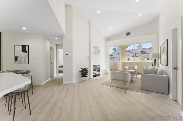 living room with light hardwood / wood-style flooring and high vaulted ceiling