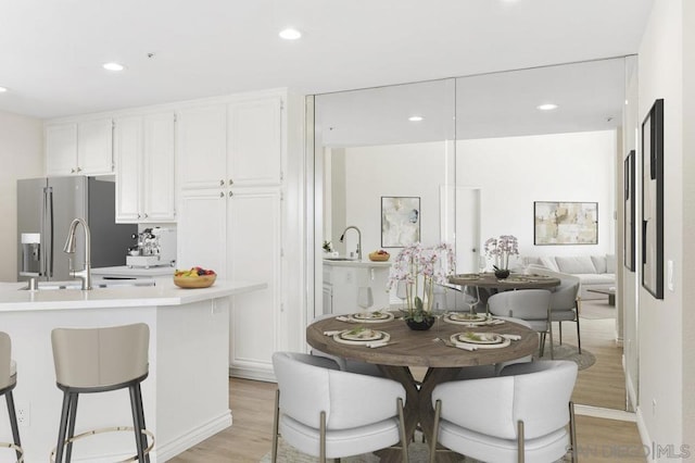 kitchen featuring white cabinets, sink, stainless steel fridge with ice dispenser, and light hardwood / wood-style flooring