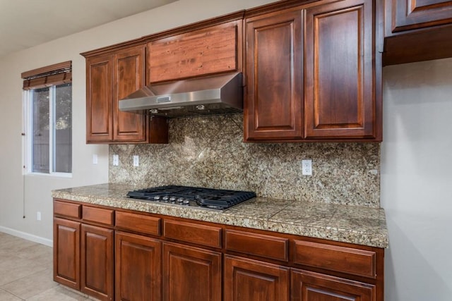 kitchen with light tile patterned floors, decorative backsplash, range hood, and stainless steel gas stovetop