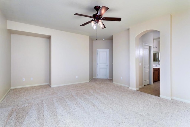 unfurnished bedroom with light carpet, connected bathroom, and ceiling fan