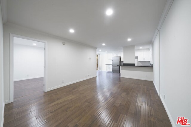 unfurnished living room with dark hardwood / wood-style flooring and ornamental molding