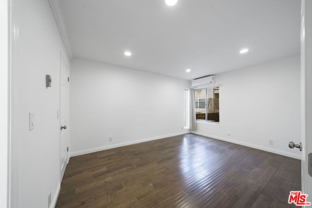 empty room featuring dark wood-type flooring and an AC wall unit