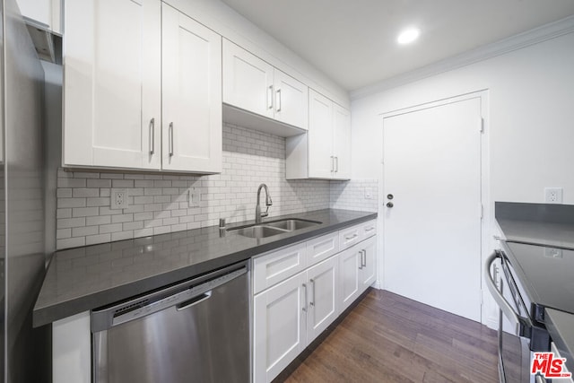 kitchen with white cabinets, dark wood-type flooring, stainless steel appliances, sink, and backsplash