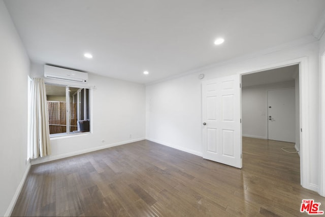 spare room featuring a wall mounted AC and dark wood-type flooring