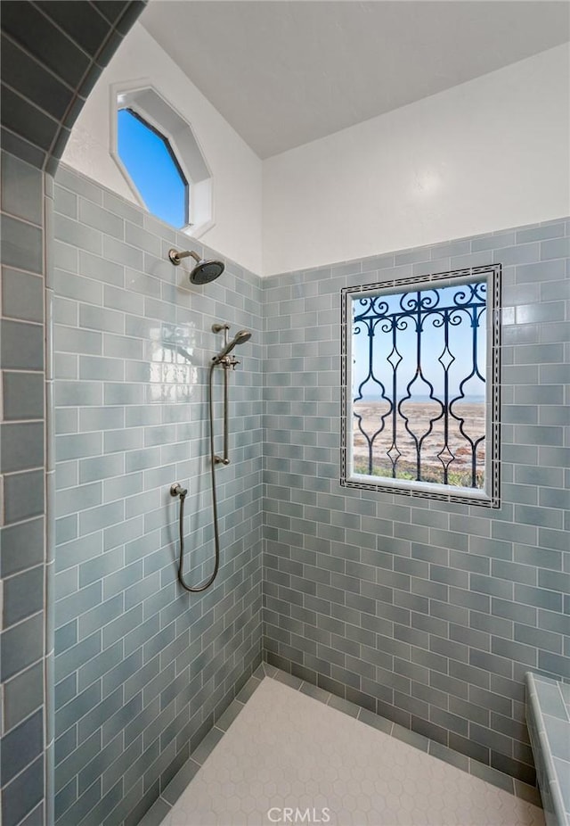 bathroom with tiled shower and tile patterned flooring