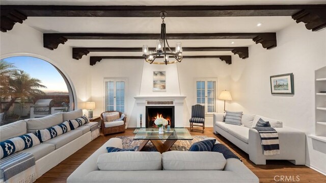 living room featuring beam ceiling, an inviting chandelier, and hardwood / wood-style floors