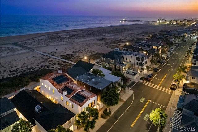 aerial view at dusk featuring a beach view and a water view