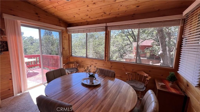 carpeted dining area featuring wooden walls, lofted ceiling, wood ceiling, and a healthy amount of sunlight