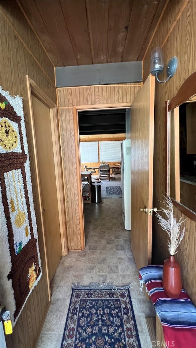 hallway featuring wood ceiling and wood walls