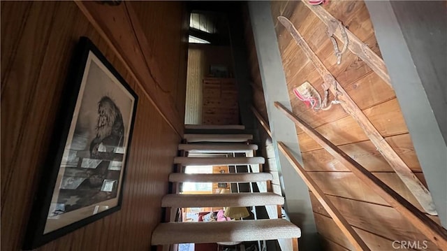 staircase featuring wooden ceiling and wooden walls