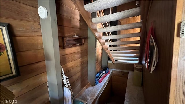 staircase featuring wooden walls