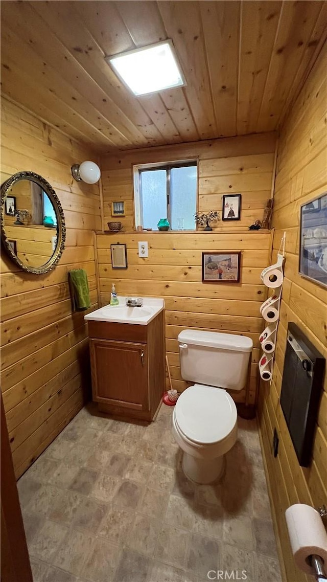 bathroom featuring toilet, vanity, wood walls, and wood ceiling