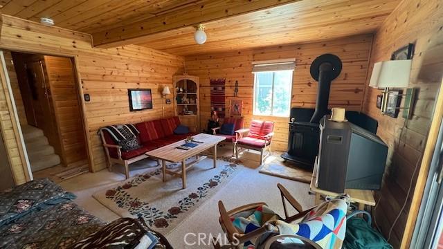 sitting room with a wood stove, beamed ceiling, and wood ceiling