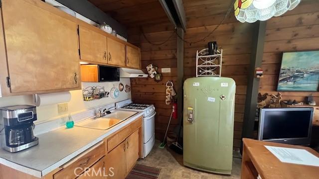 kitchen with white range with gas stovetop, sink, and wooden walls