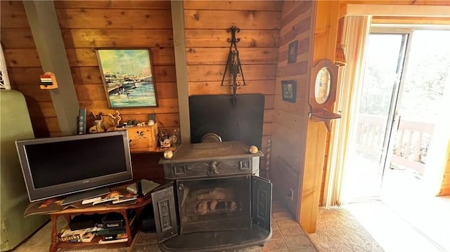 interior space featuring carpet floors, wood walls, and a wood stove