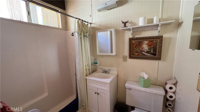 bathroom featuring toilet, walk in shower, and vanity