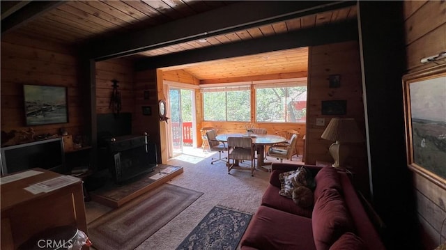 carpeted living room featuring a wood stove, vaulted ceiling with beams, wood ceiling, and wooden walls