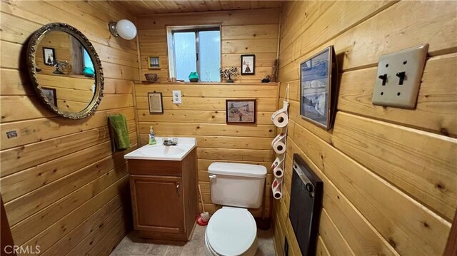 bathroom featuring toilet, vanity, wooden walls, and wooden ceiling