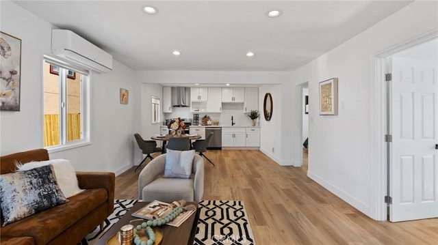 living room with light wood-type flooring, sink, and a wall unit AC