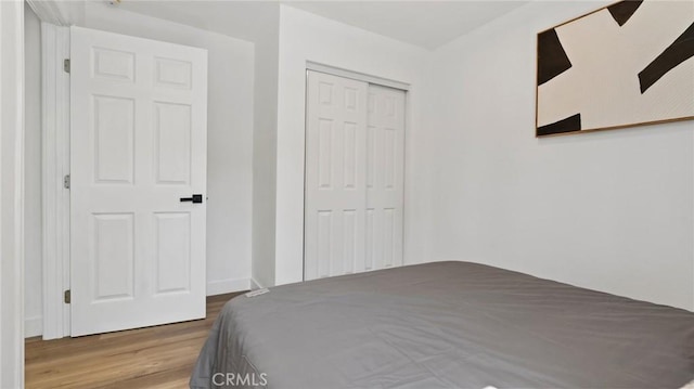 bedroom with a closet, light hardwood / wood-style flooring, and ceiling fan