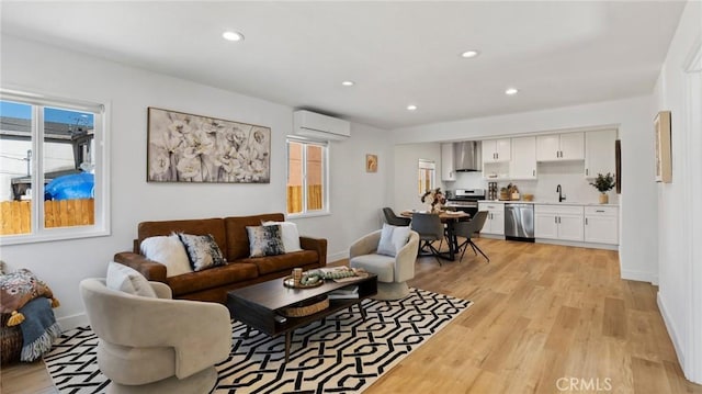 living room with light hardwood / wood-style floors, sink, and a wall unit AC