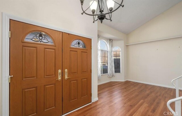 entrance foyer featuring vaulted ceiling, a chandelier, and wood-type flooring