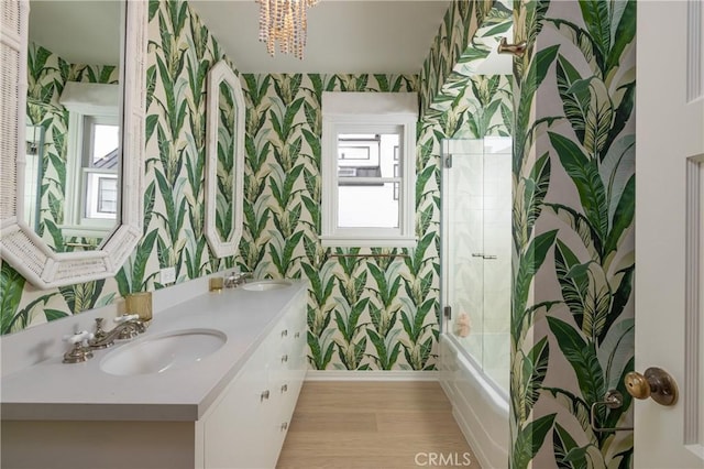 bathroom featuring combined bath / shower with glass door, a chandelier, hardwood / wood-style floors, and vanity