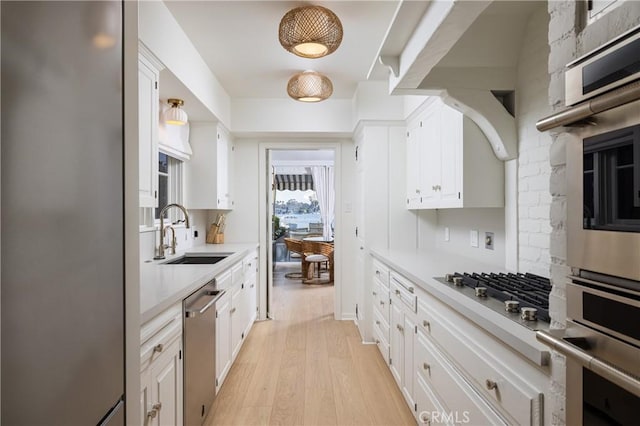 kitchen with sink, white cabinetry, stainless steel appliances, and light wood-type flooring