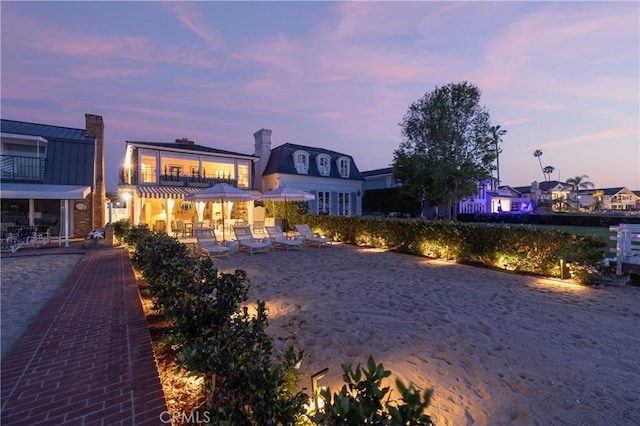 back house at dusk with a patio area and a balcony